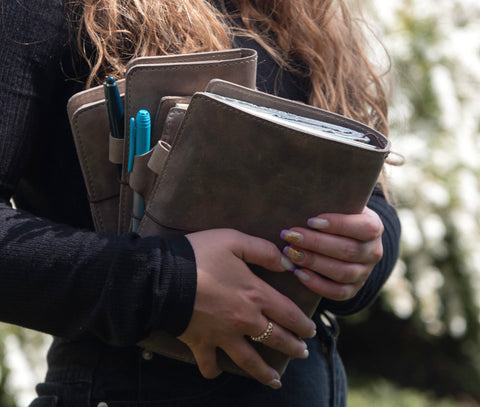 Gray leather travelers notebook covers. Person holding journal covers.