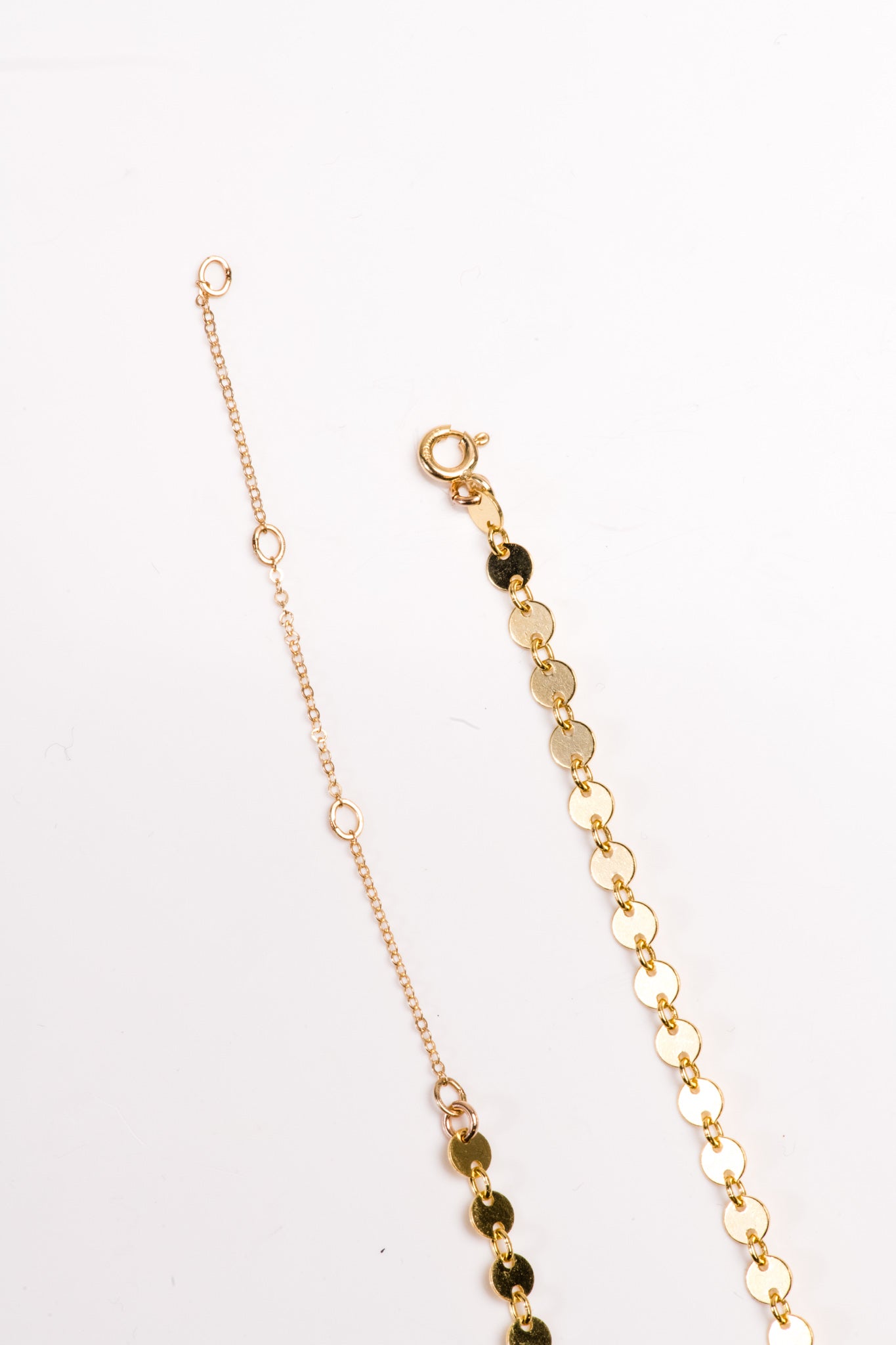 Two types of delicate gold chains with clasp closures on a white background.