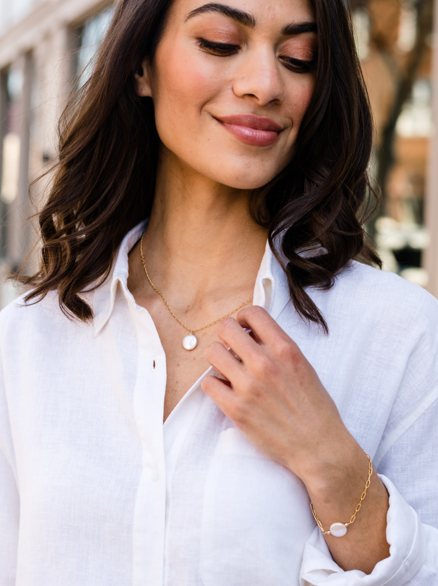 Woman in white shirt with a gold necklace and bracelet.