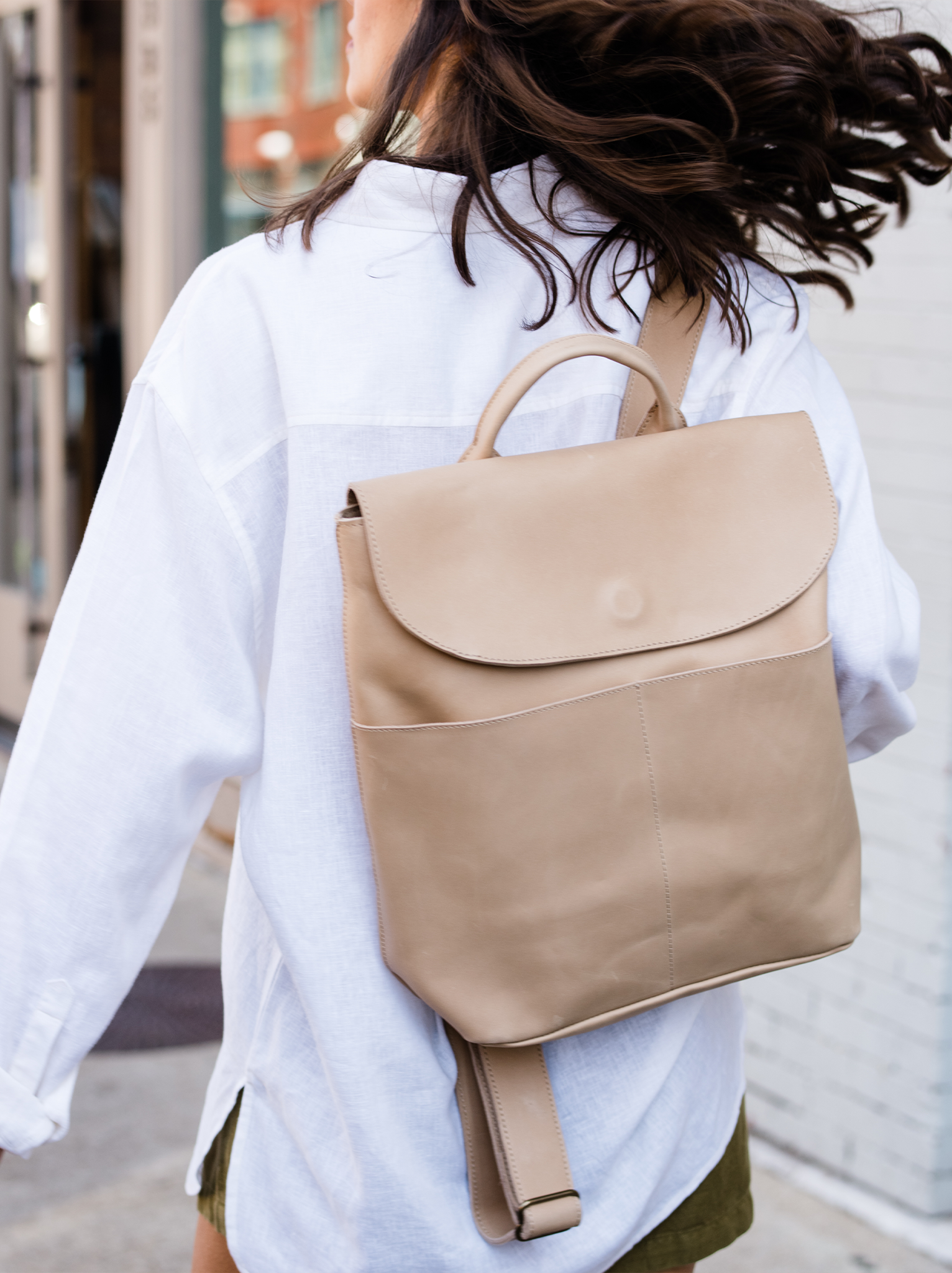 Woman with a beige backpack on a city street.
