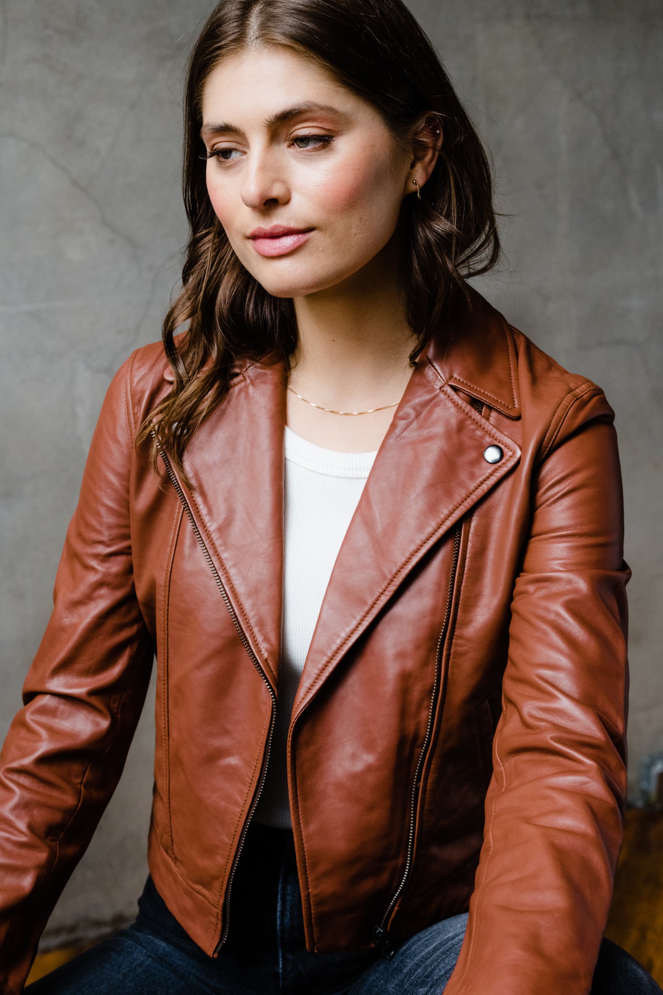 Woman in brown leather jacket looking to the side.