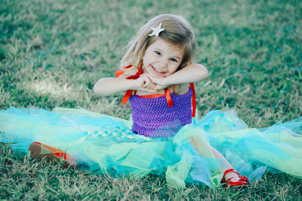 Young girl in a tutu sitting in the grass 