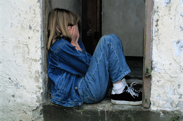 girl sitting in a doorway with her face in her hands