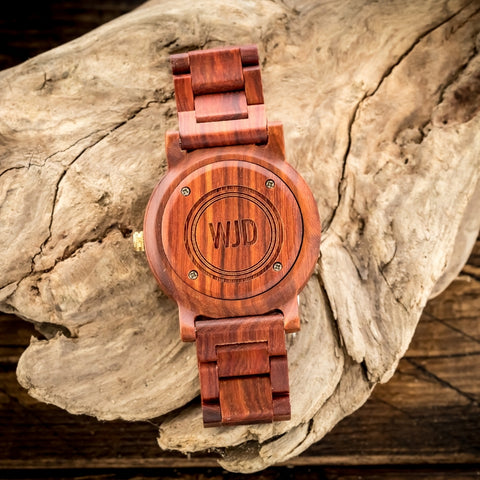 engraved red sandalwood wood watch laying on a rock
