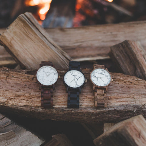 three watches laying on a wooden log