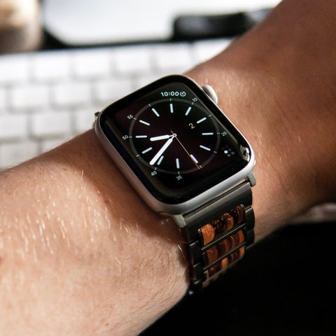 apple watch with band on man's wrist in front of computer