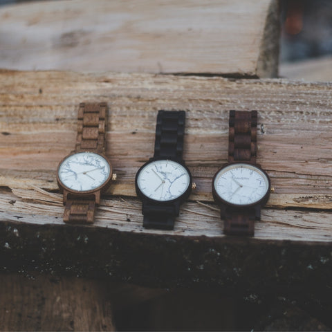 three wooden watches laying outside on wood