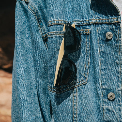 wooden sunglasses in jean jacket pocket