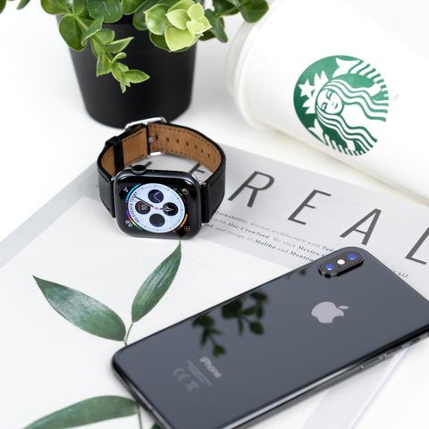 world clock watch and phone lying on book next to coffee and plant