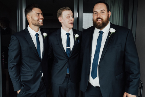 groomsmen wear formal dark navy suits on wedding day