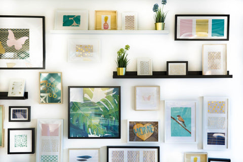 White wall with several pieces of wall art in different designs and sizes