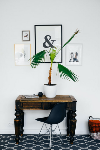 Small rustic table leaning against a decorated white wall
