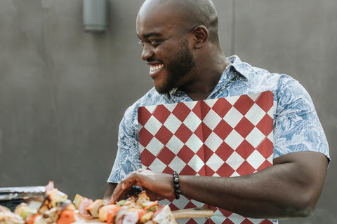 Man wearing a red and white diamond NEATsheet while eating barbecue.
