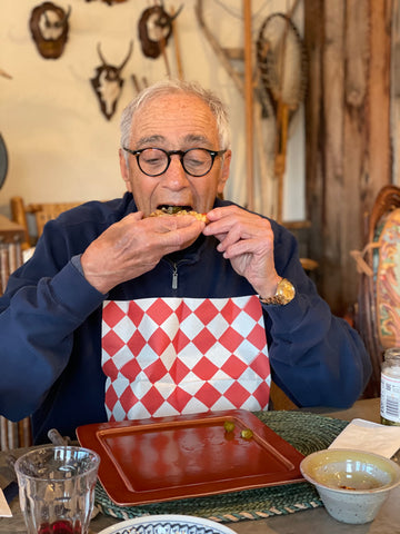 A dad wearing a red and white diamond NEATsheets while eating pizza.