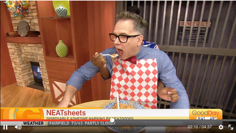 Cody Stark, host of Good Day Sacramento, wearing a NEATsheet and eating spaghetti during a show segment.