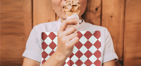 Girl eating an ice cream cone wearing a Red & White Diamond NEATsheet, a disposable clothing protector with easy-to-use adhesive tabs.
