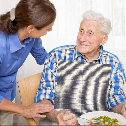 Elderly man wearing a blue ticking NEATsheet while eating lunch. 