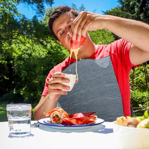 Man eating lobster with dripping butter while wearing a NEATsheet adhesive bib.