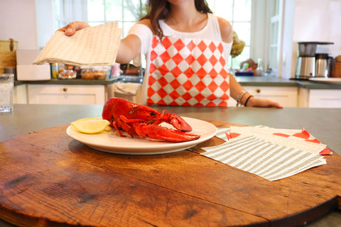 Woman reaching for lobster while wearing a NEATsheet adhesive bib.