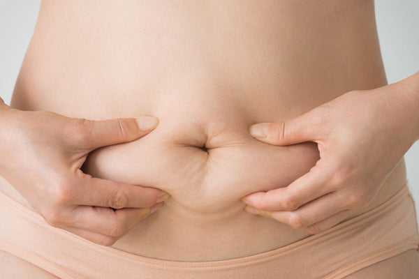 woman squeezing mummy tummy with diastasis recti