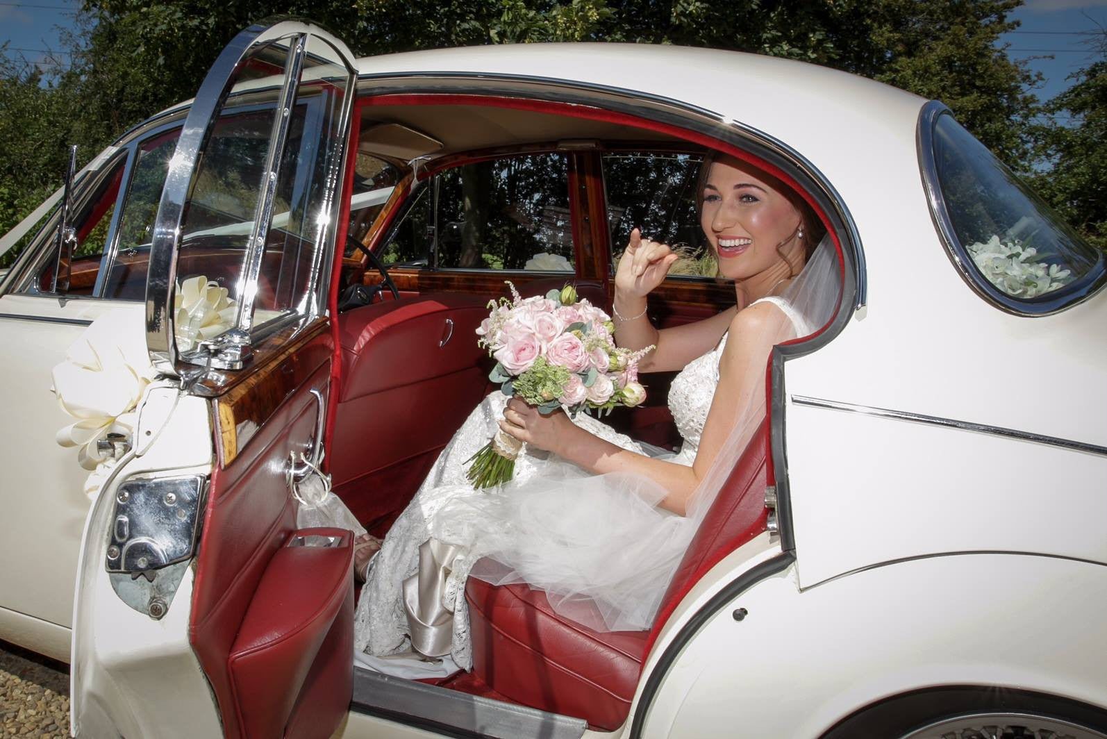 Bride with pink Rose bridal bouquet in the wedding car.
