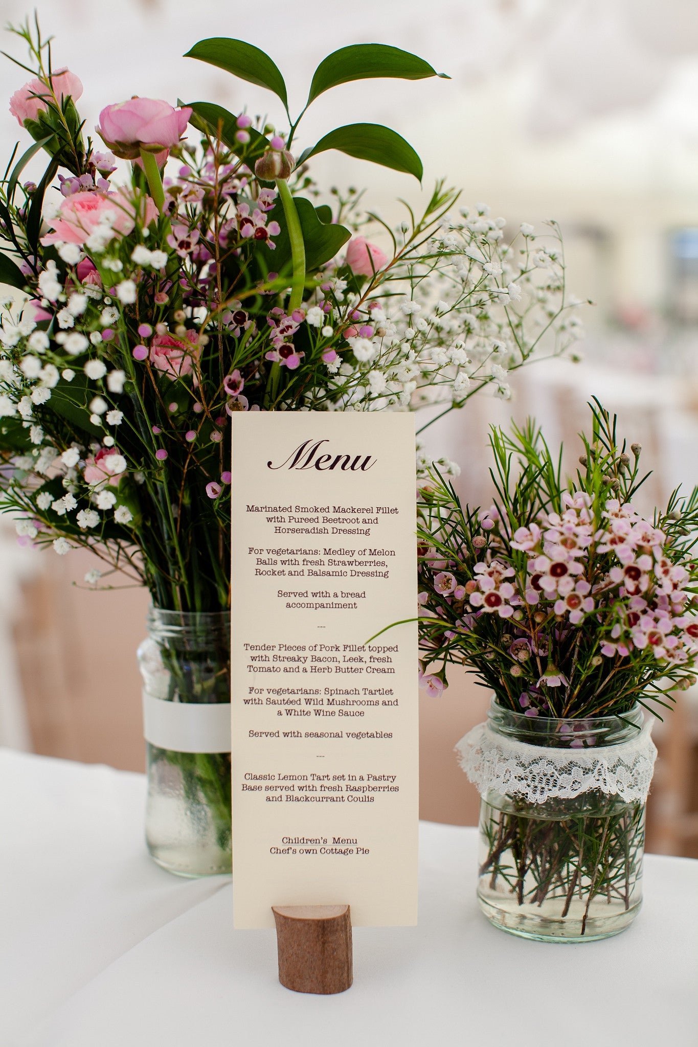 Wedding menu with floral table arrangements in jam jars.