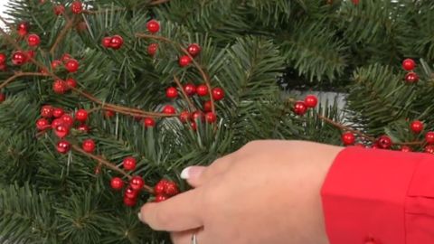 putting thin red berry on a green garland