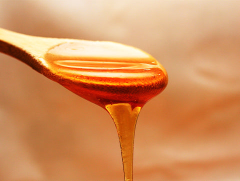 dripping honey off a wooden spoon