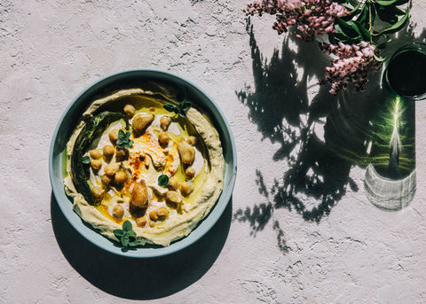 An aerial photo of a bowl of triple garlic hummus on a table