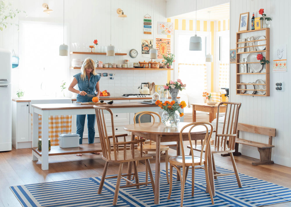 A woman stands at a kitchen bench. A blue rug made by Double is under the table