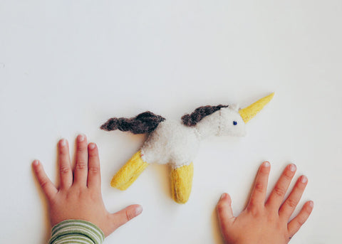 photo of a handmade felt unicorn and two toddler hands for Lunch Lady Magazine