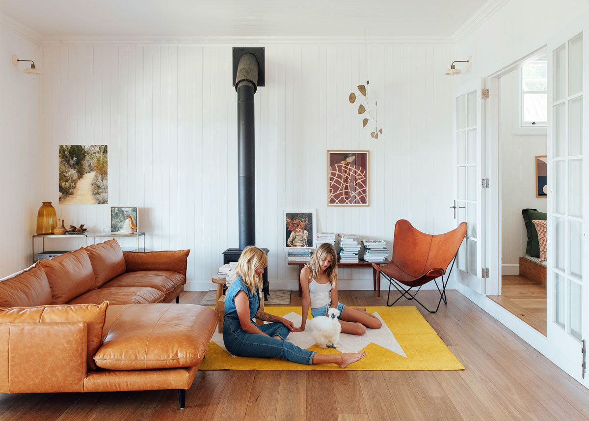 Yvonn Deitch sits on the floor on a Double brand rug with a chicken and child