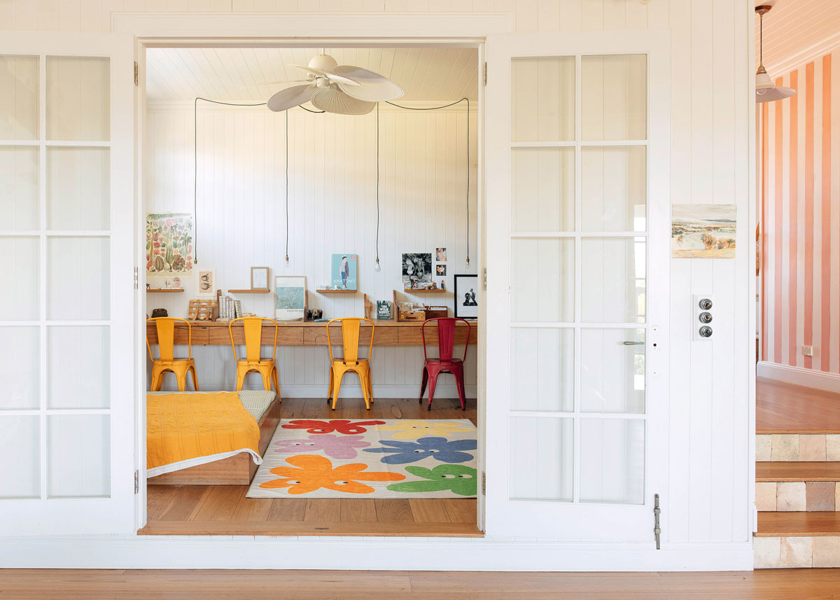 A rug with large coloured flowers on it is featured in a room with a desk