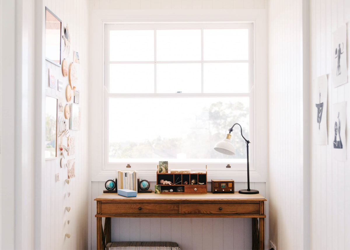 A wooden desk under a window in the home of Yvonn Deitch for Lunch Lady Magazine