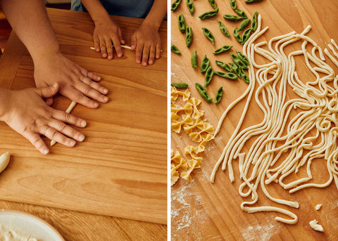Photo of kids hands making homemade pasta on a wooden table