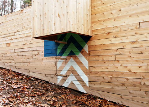 a photo of the side of the wooden five fields playground. Arrows are painted on the side and pointing up a wooden shaft.