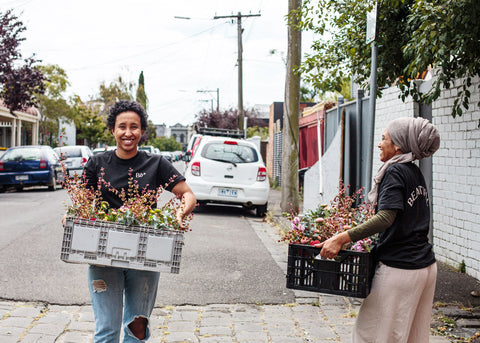 a photo of two refugee women on the streets of Melbourne holding crates of floral arrangements for The Beautiful Bunch