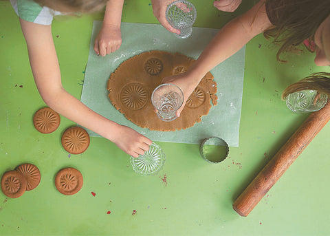 Image of kids using crystal glasses to cut out gingerbread dough biscuits