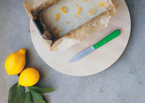 lemon and coconut no-bake slice on a cutting board beside fresh lemons