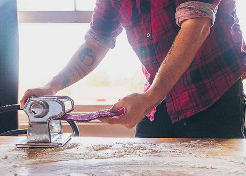 a man rolls out purple pasta dough for lunch lady magazine