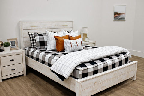 An image of a bedroom with a queen white bedframe featuring our Checked Out Beddy's with our Wild About Black and White Accessory Bundle.