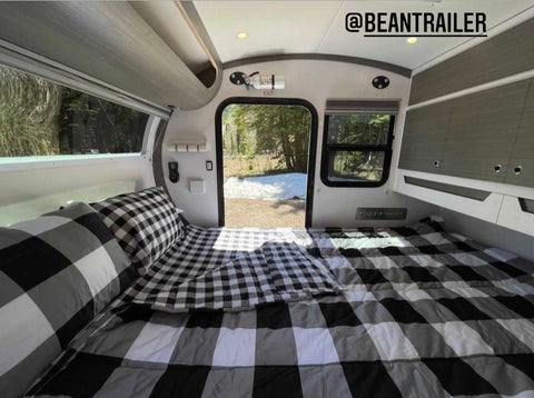 An image of our Checked Out Beddy's in a teardrop trailer with the door open showing the beautiful outdoors.
