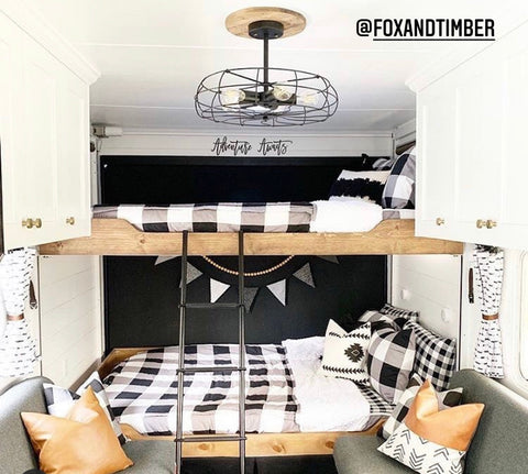 The image of the interior of an RV, showing a set of raw wood built-in bunks. Bunk are showing Beddy's black and white buffalo check Checked Out Beddy's. Two couches sit in front of the beds with faux leather accent pillows.