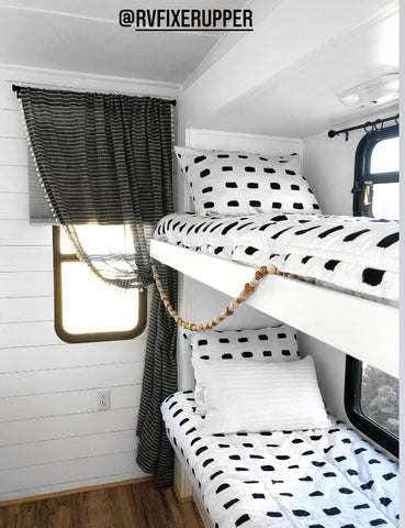 The inside view of a set of RV bunk beds on the wall to the right. Both beds feature Beddy's white with black dashes Dash Beddy's.