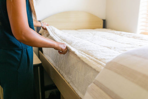 A woman neatly arranging a mattress on a bed, preparing it for use. The image showcases zipper bedding, ideal for dorm rooms.