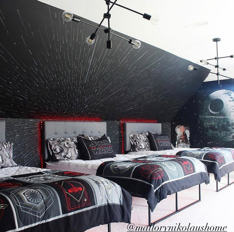 Three full size beds sit in front of a dark black wall. All three beds feature our Love at First Beddy's with Star Wars themed pillow shams and accent blanket at the foot of the bed.