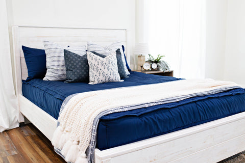 A queen bed made with navy zipper bedding