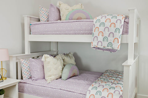  A white bunk bed adorned with purple and rainbow pillows, creating a vibrant and cozy sleeping space.