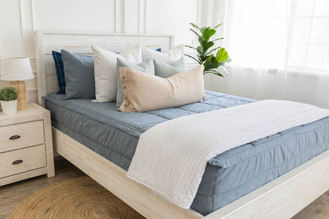A bed with blue pillows and a white nightstand.
