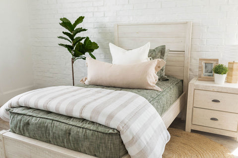 A kid's bed with a white headboard and a green & white striped comforter, featuring green zipper bedding.